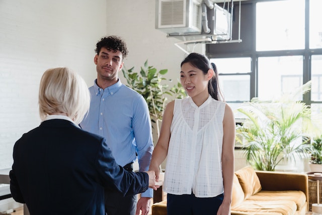 landlord shaking hands with two tenants in their apartment